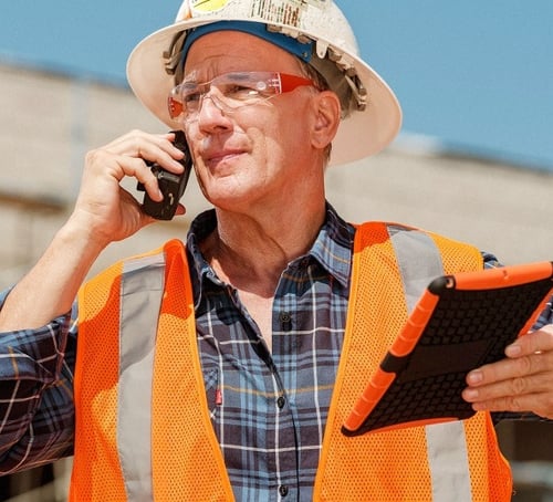 person on construction site with device in hand