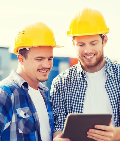 smiling builders in hardhats with tablet pc